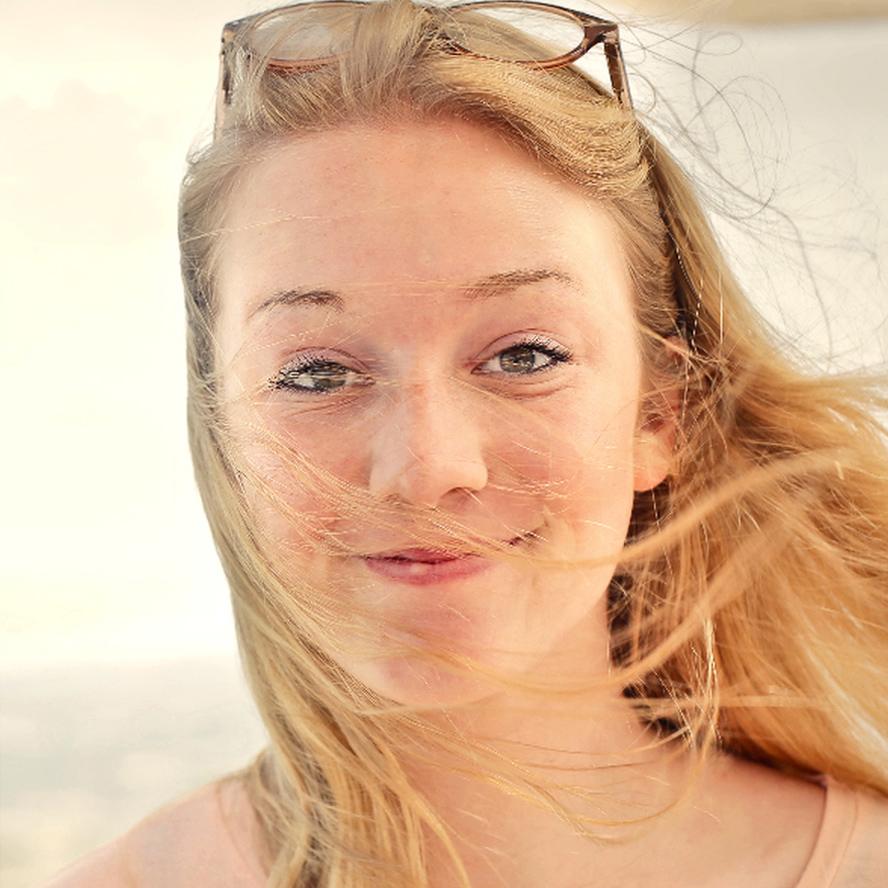 Silhouette of a woman's profile. She is wearing glasses and has a pony tail. The background is a warm red color.
